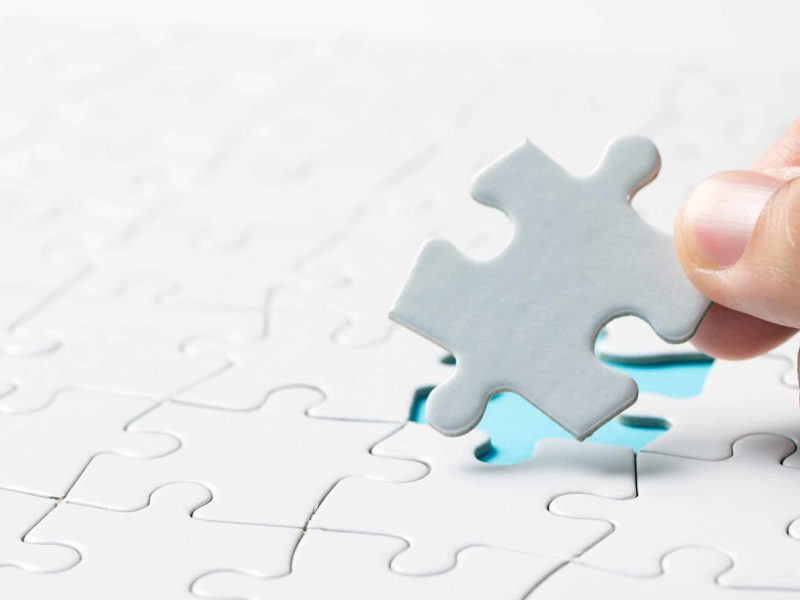 Hand placing the last jigsaw puzzle piece or holding missing jigsaw puzzle piece down in to the place